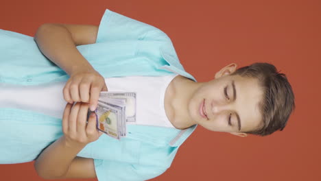 Vertical-video-of-Boy-counting-money-looking-at-camera.
